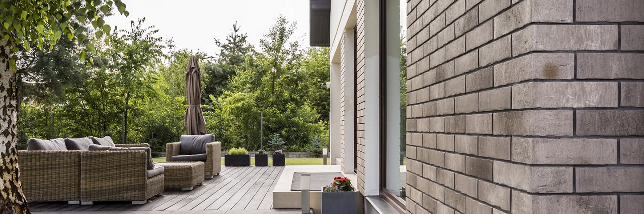 Panoramic shot of a patio with wooden floor and a rattan furniture set; Shutterstock ID 755448436