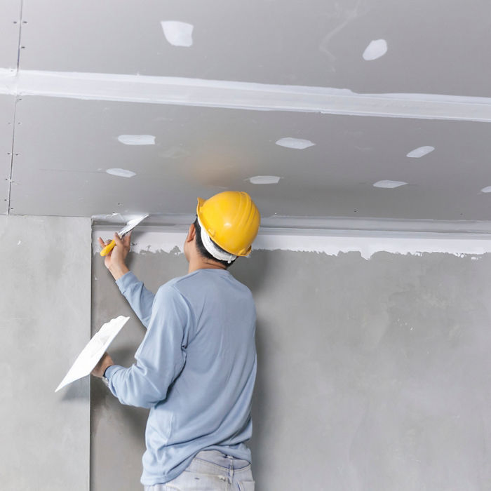 Man with yellow helmet working on a ceiling