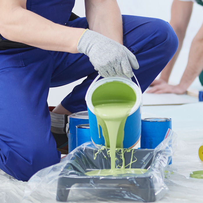 House painter pouring green wall paint into tray; Shutterstock ID 704928292; purchase_order: CON; job: ; client: ; other: 