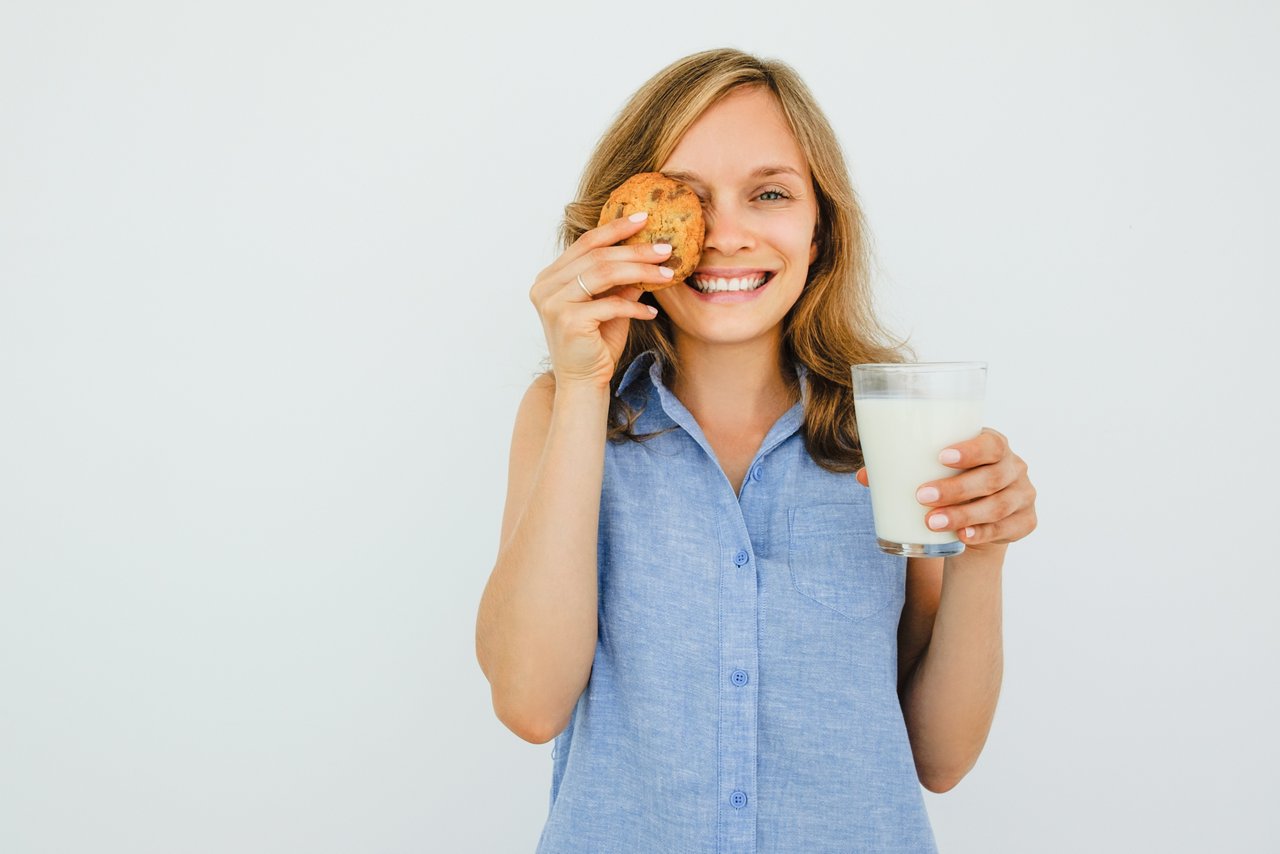Woman Holding Glass of Milk and Cookie; Shutterstock ID 689900761