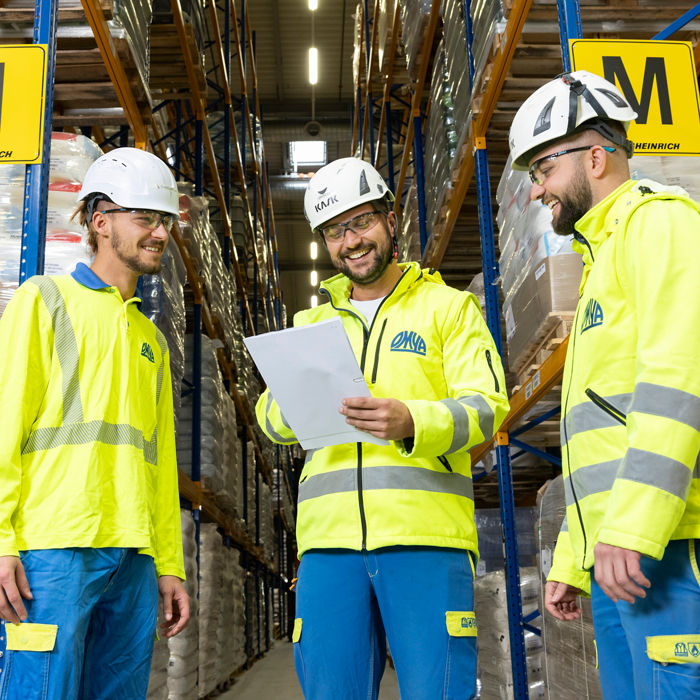 Three employees using protective equipment in a warehouse