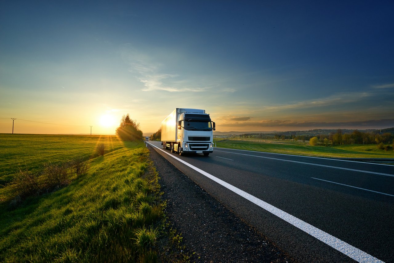 White truck driving on the asphalt road in rural landscape at sunset; Shutterstock ID 720072589