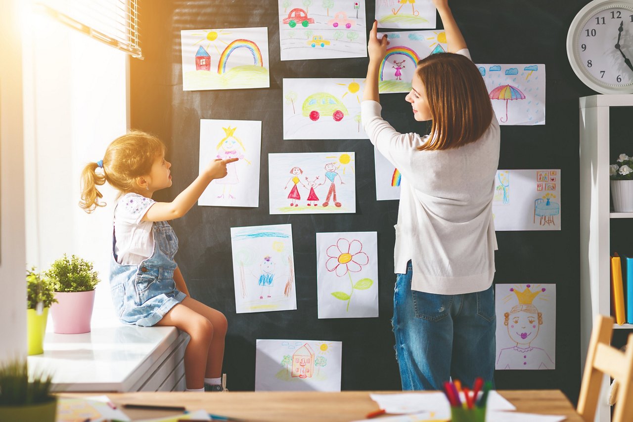 Omya Hydrocarb - Mother and child girl hang their drawings on the wall