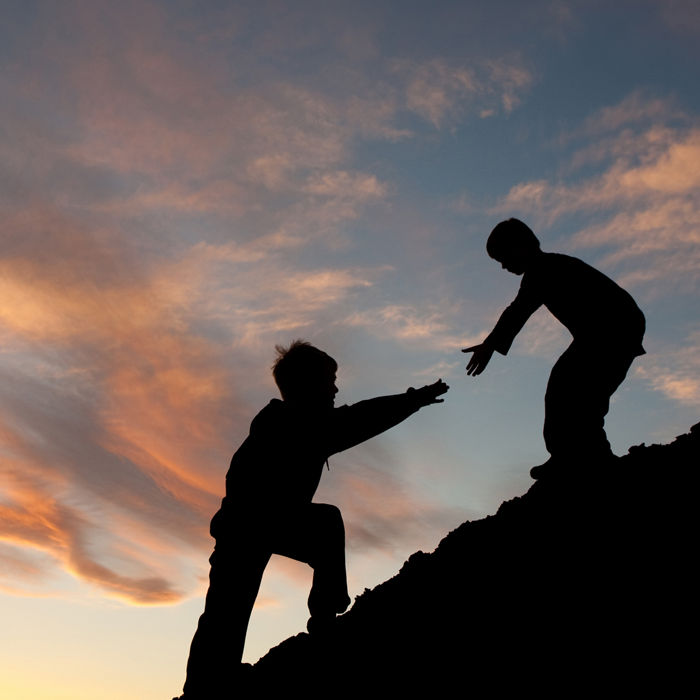 Two kids helping each other going up a hill