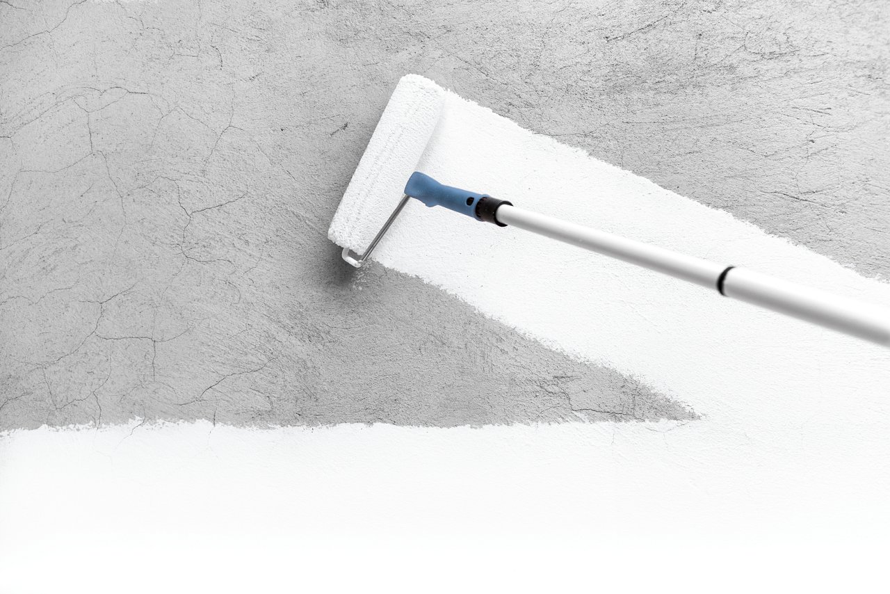 Paintbrush painting a wall white