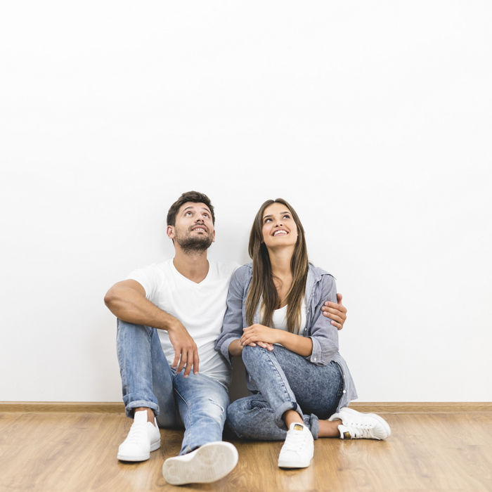 The happy couple sit near the white wall; Shutterstock ID 717572647