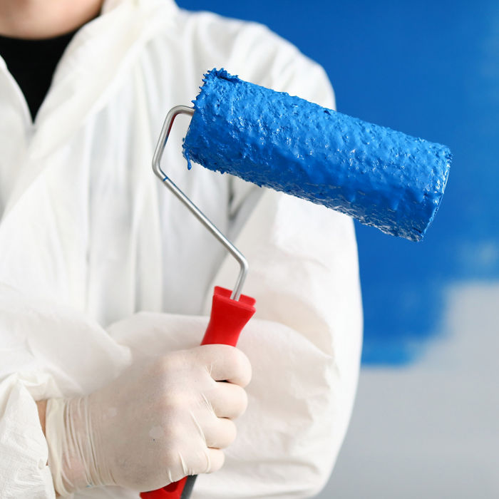Close-up of person painter holding roller covered in blue paint. Professional worker wearing protective uniform and gloves. Copy space in right side. Renovation concept; Shutterstock ID 1743262391; purchase_order: CON; job: P&C - Decorative paints, main applications; client: ; other: 