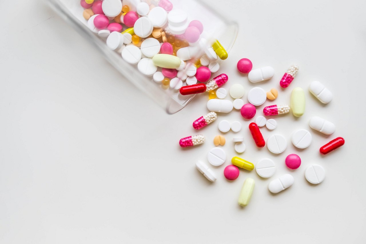 Pills of different size and color on a table