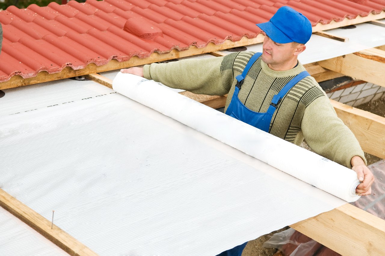 worker installing thermal insulation layer on the roof of a house