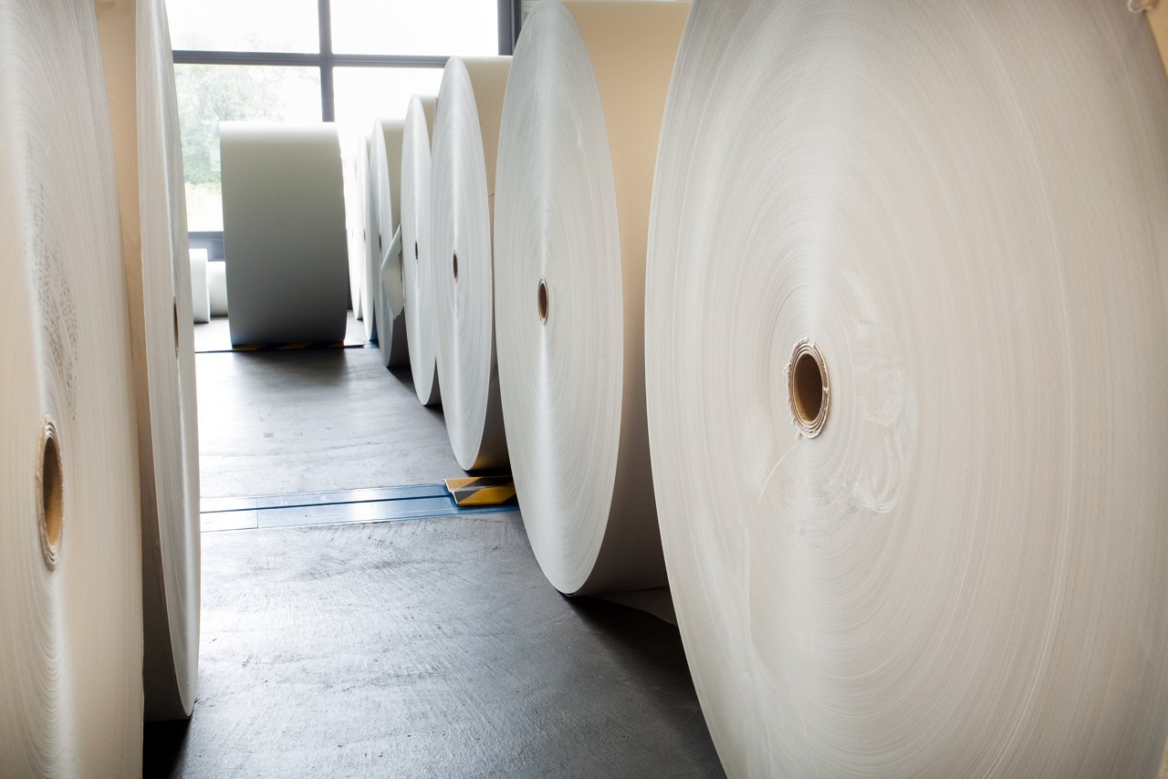 Paper rolls lined up waiting to be put on printing press