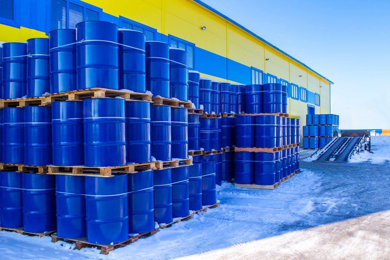 Blue containers are palletized in stock. Metal barrels for chemicals. Barrels are ready to be shipped from stock. Warehouse shipping activities. Chemical industry.