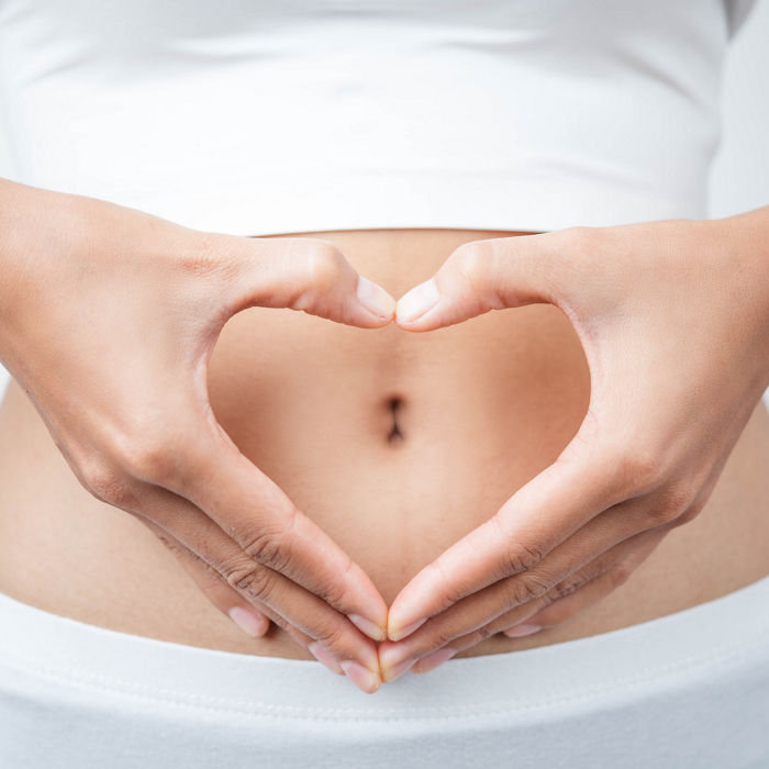 Close up of woman's hands made heart on belly isolated on white background.health care concept.; Shutterstock ID 583399804