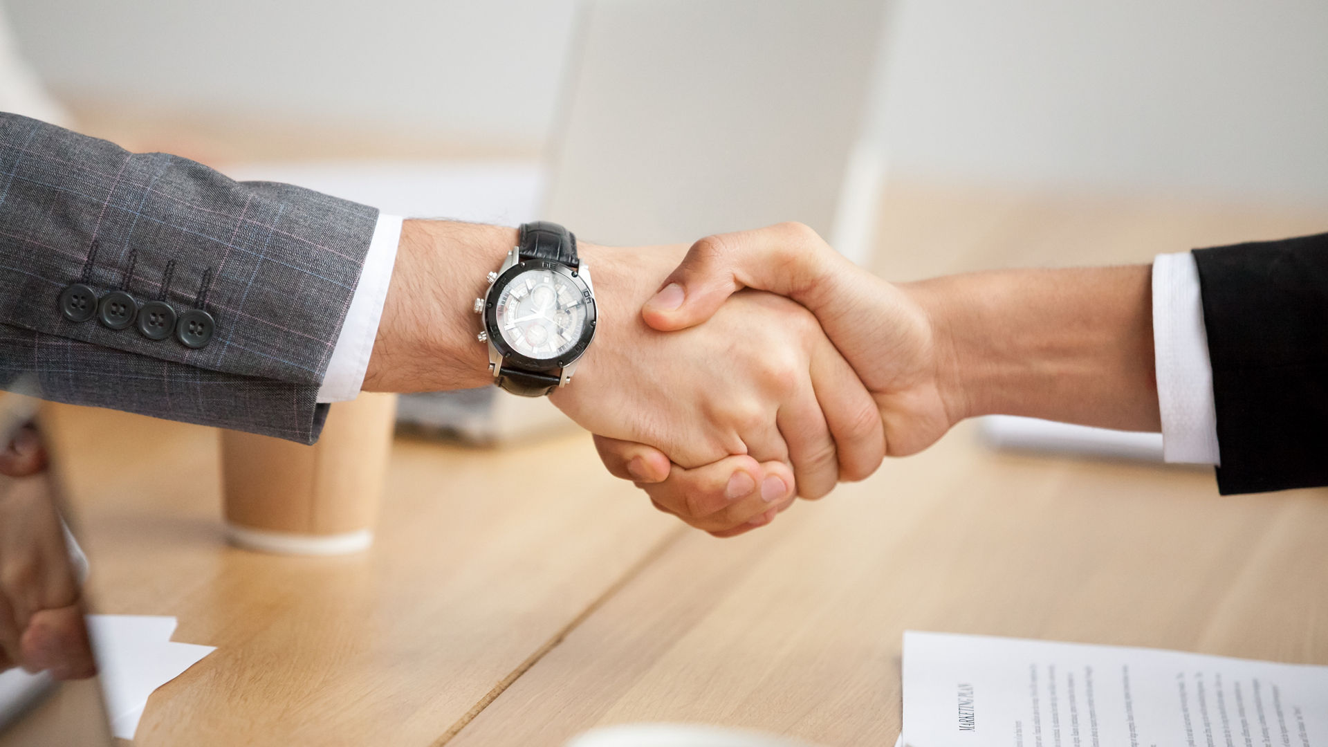 Two businessmen in suits shaking hands as concept of trust, good partnership deal, signing contract agreement at meeting, gratitude for help support in business