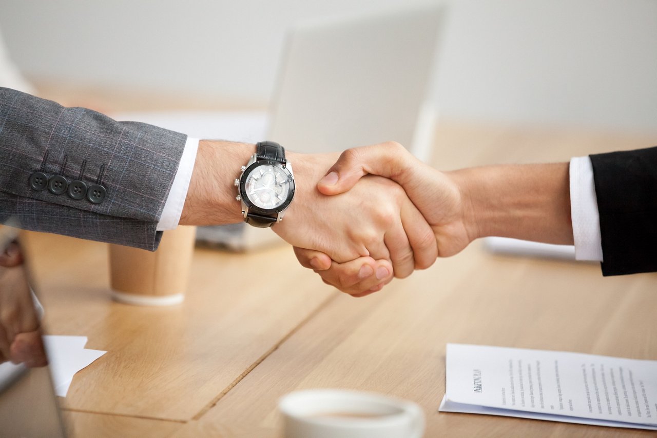 Two businessmen in suits shaking hands as concept of trust, good partnership deal, signing contract agreement at meeting, gratitude for help support in business