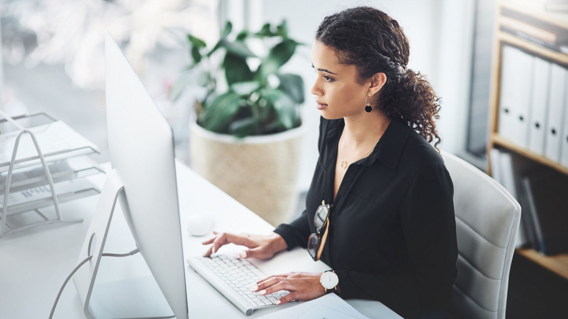 Woman working at an office typing on a computer 