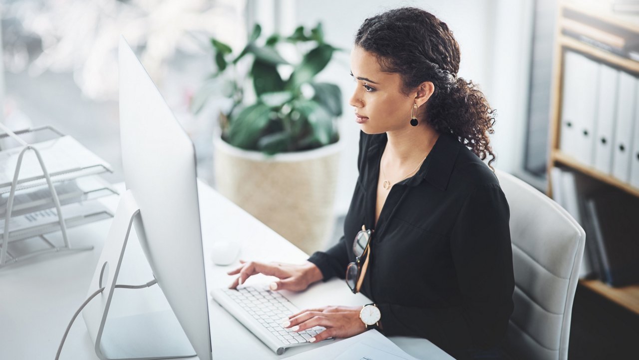 Woman working at an office typing on a computer 