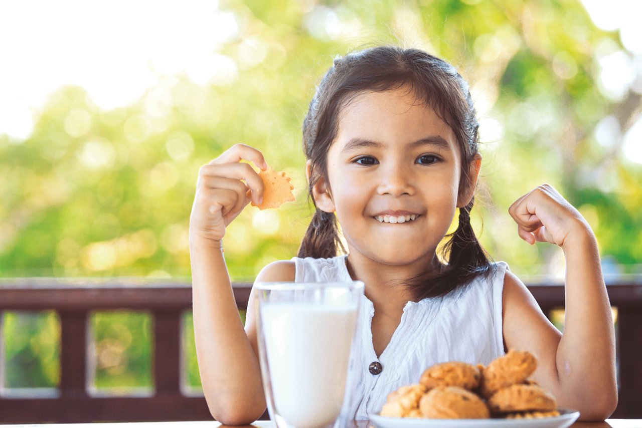Girl with cookies and a glass of milk looking happy