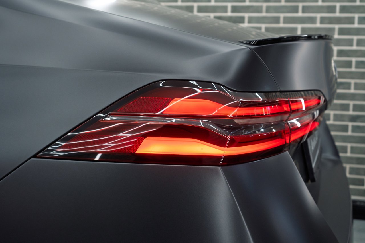 LED turn signal in the rear brake light of the car. Modern car lantern, close-up. Detail on the rear light of a black matte car. Close-up of a modern black sedan automobile with LED red taillights.