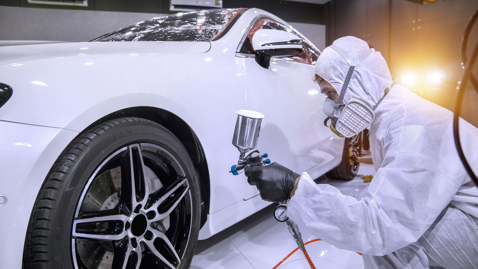paint technician or motor vehicle finisher painting a white car
