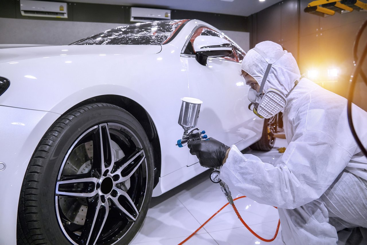 paint technician or motor vehicle finisher painting a white car