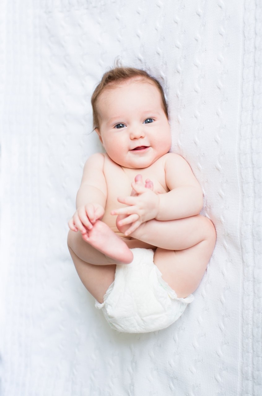 Funny chubby baby playing with its feet; Shutterstock ID 119402965