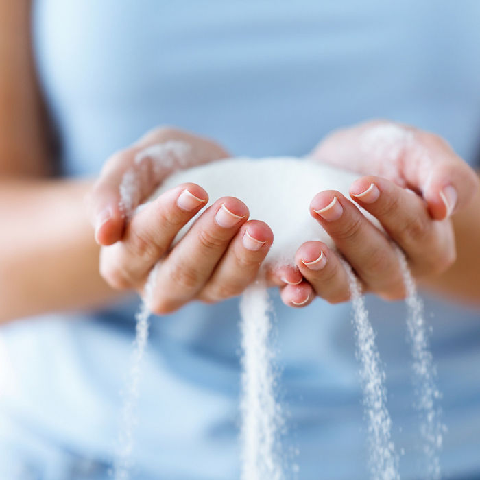 Close-up of white sugar in the woman hands. Heap of white sugar.; Shutterstock ID 1217732431; purchase_order: POL_Website_Recycled CaCO_Omyaloop FC; job: ; client: ; other: 