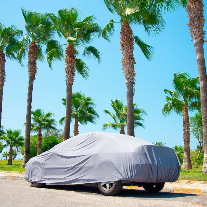 The car is in the parking with auto cover from the sun surrounded by palm trees. Hot countries, protection from heating the car.; Shutterstock ID 1221831919; purchase_order: POL Website Automotive_Plastisols; job: ; client: ; other: 