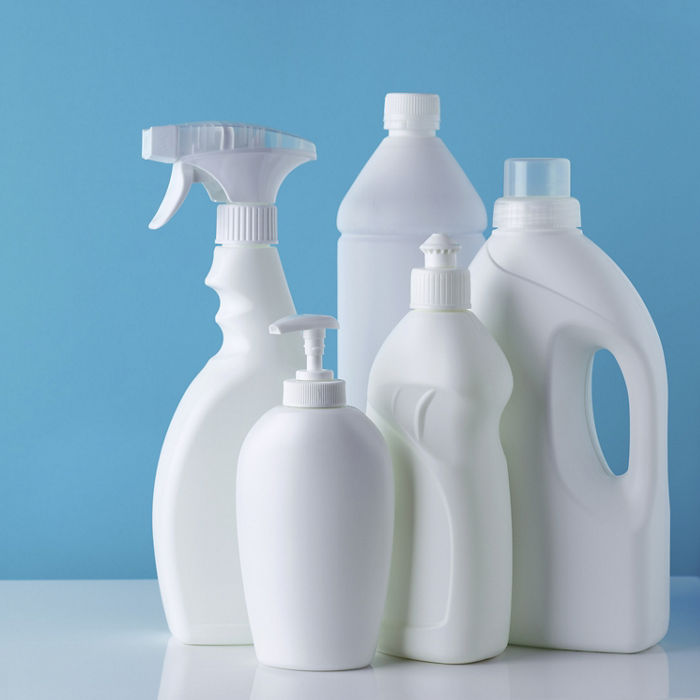 Set of white bottles of different cleaning procucts on blue background with empty space for text