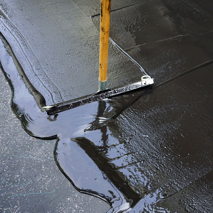 Person sealing asphalt driveway