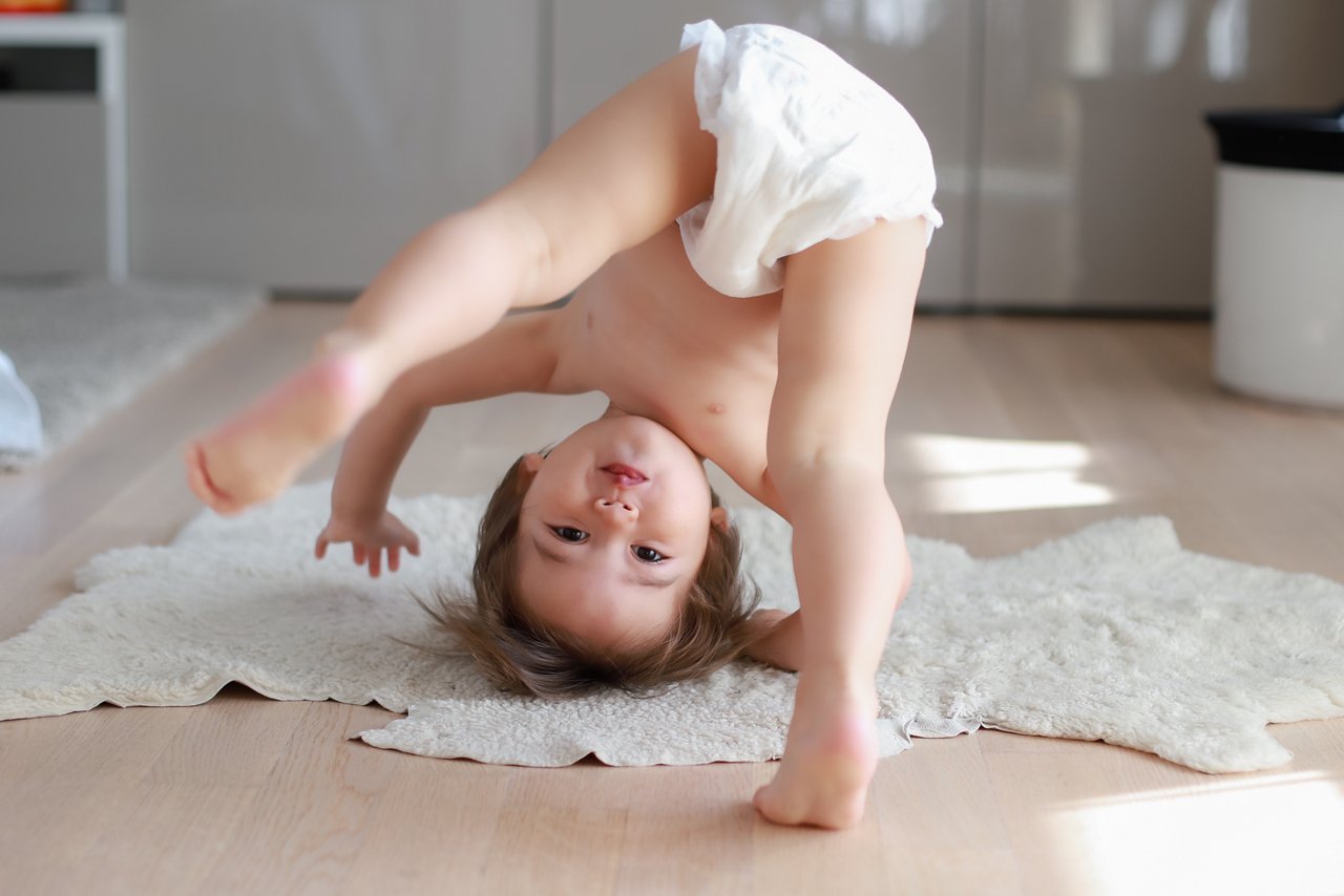 Cute and funny baby boy wearing diaper bending over