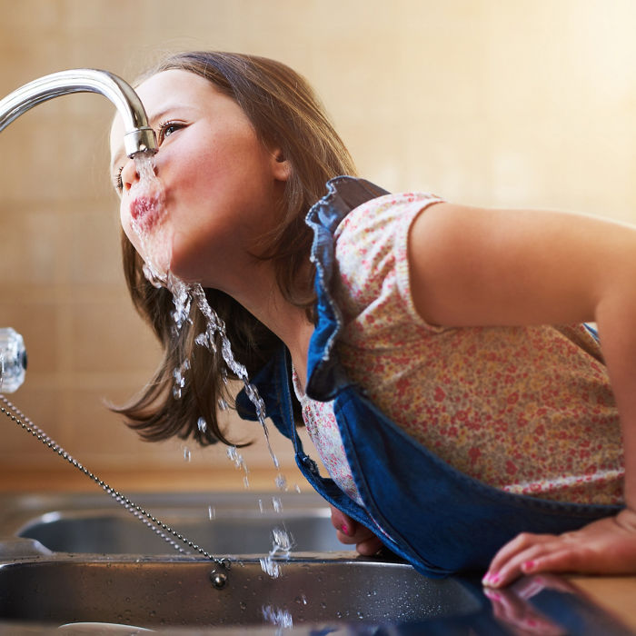 The thirst is real. Shot of a little girl drinking water directly from the kitchen tap at home.; Shutterstock ID 2169380743; purchase_order: -; job: -; client: -; other: -