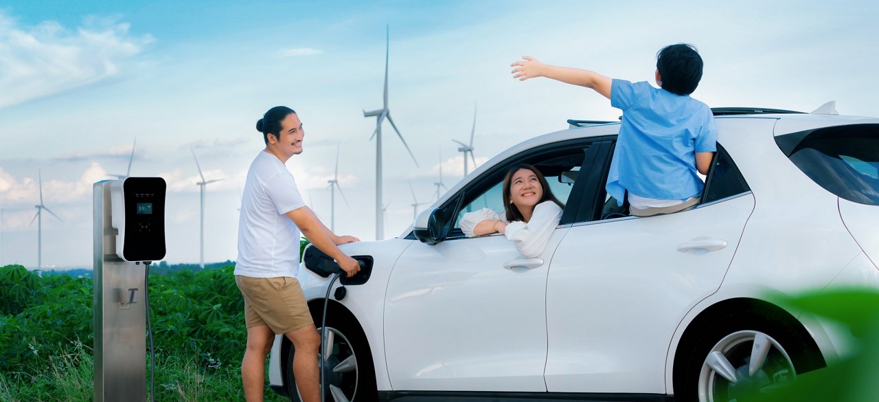 Concept of progressive happy family enjoying their time at wind farm with electric vehicle. Electric vehicle driven by clean renewable energy from wind turbine generator for charging station.; Shutterstock ID 2282025139; purchase_order: POL Website Automotive_Engineered materials ; job: ; client: ; other: 