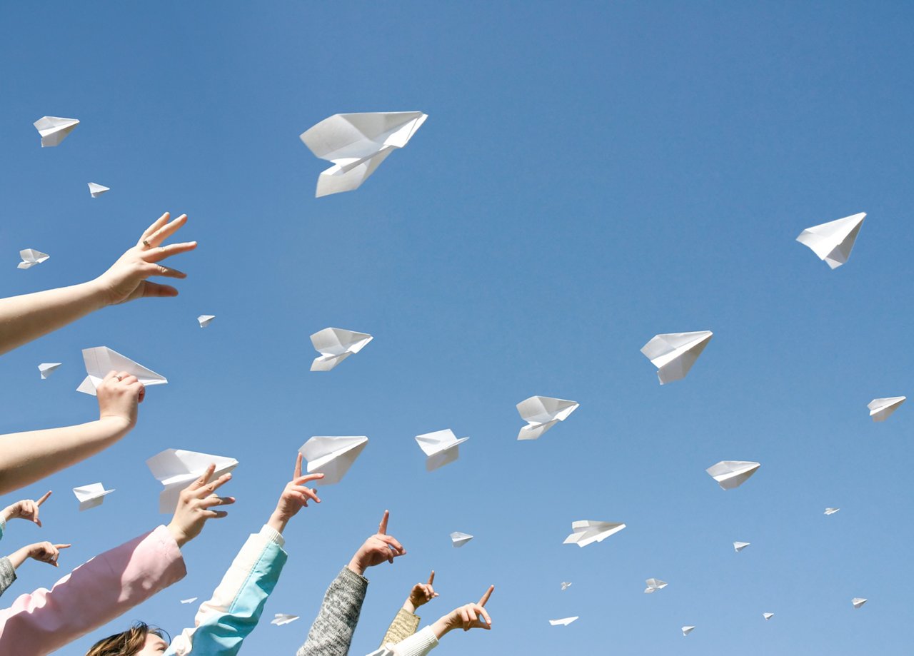 Omya Multifill - group of child arms throwing fleet of paper airplanes