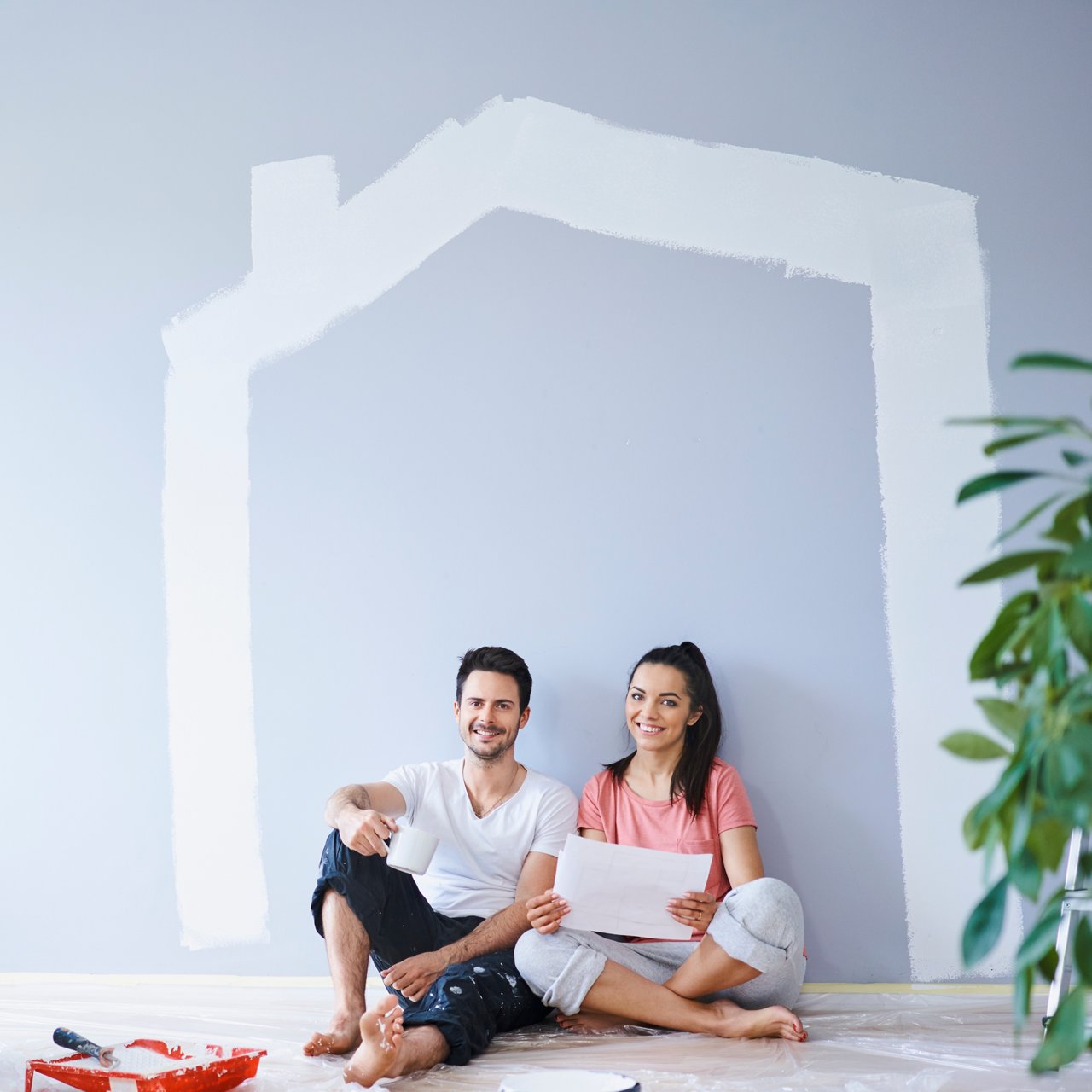 Happy couple taking break from painting walls in new apartment
