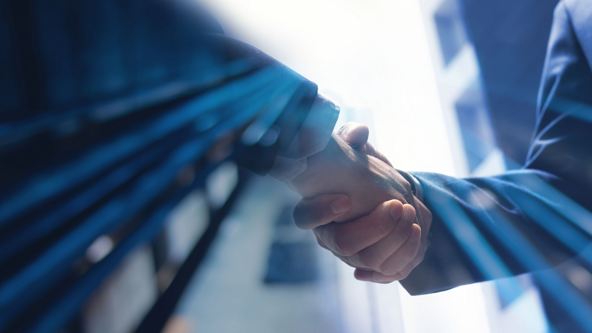 two people shaking hands with office buildings in the background