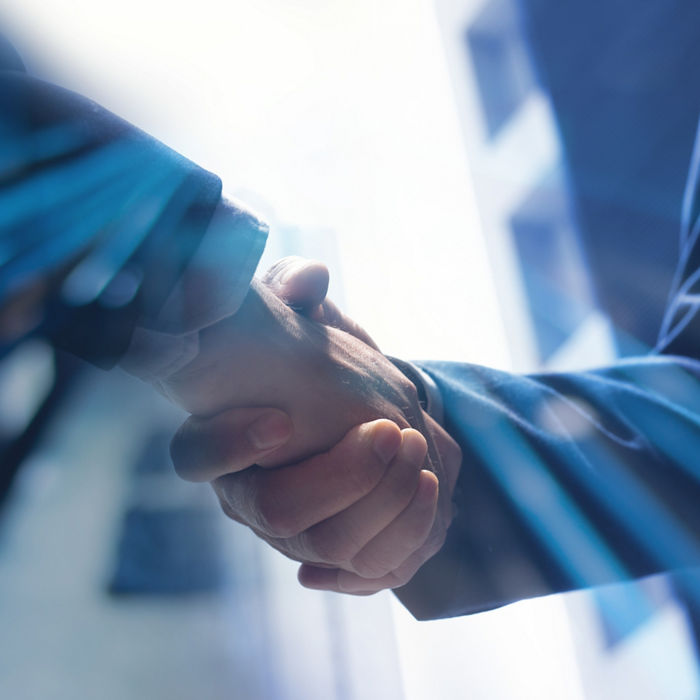 two people shaking hands with office buildings in the background